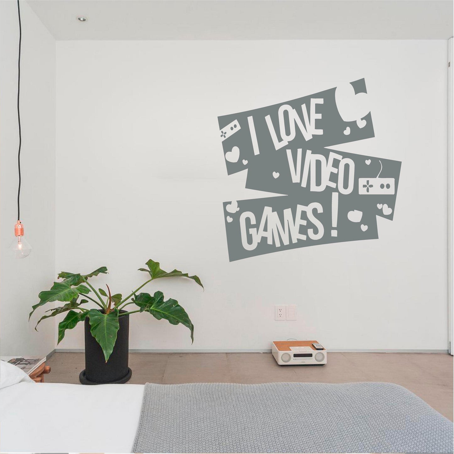Grey I Love Video Games wall decal with controllers and hearts above a bedside ledge with a plant and radio.