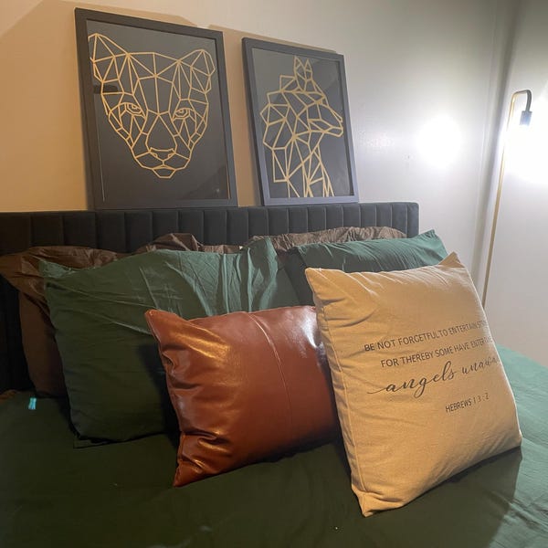 Two framed gold geometric animal designs displayed above a bed.