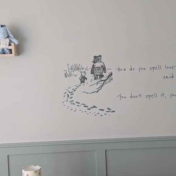 Black illustrated quote on a nursery wall above green wall panelling.