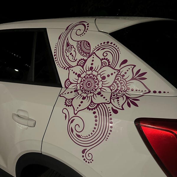 Purple floral mandala decal on the rear side panel of a white car.