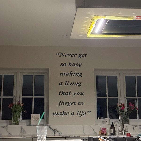 Black multiline custom quote applied to a wall between two windows.