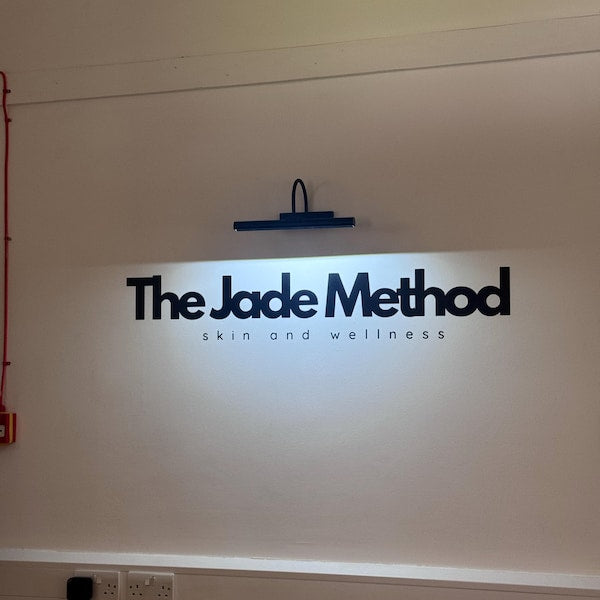 Black The Jade Method lettering on a wall under a picture light.