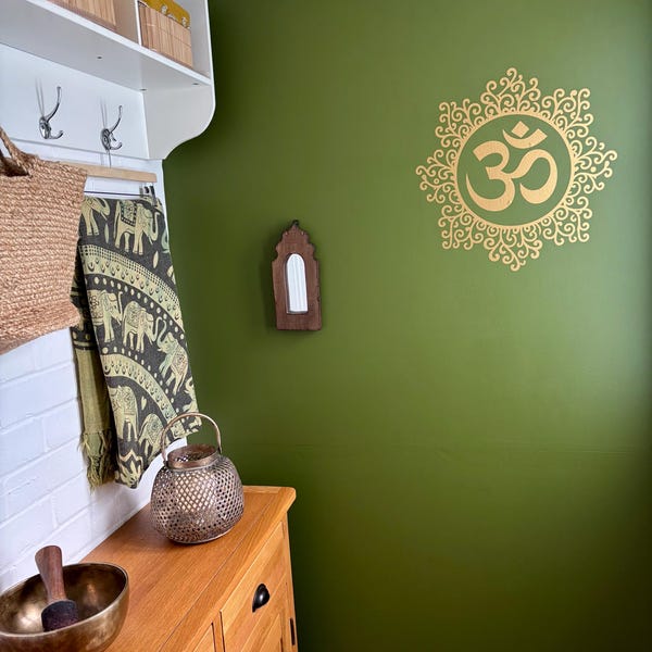 Gold Om and ornamental circle decal on a green wall.