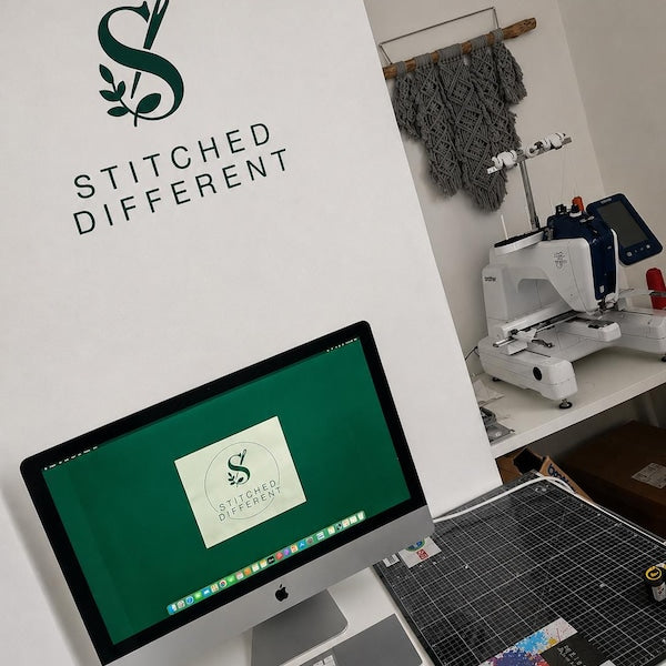 Green Stitched Different logo on a wall above a sewing workspace.