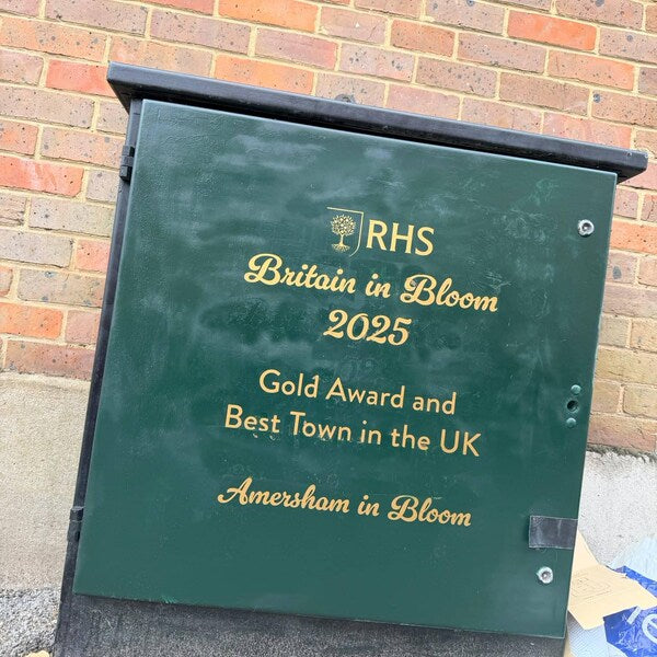 Gold Britain in Bloom award lettering on a green outdoor cabinet.