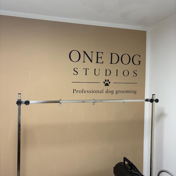 Black One Dog Studios logo on a wall above a dog grooming area.
