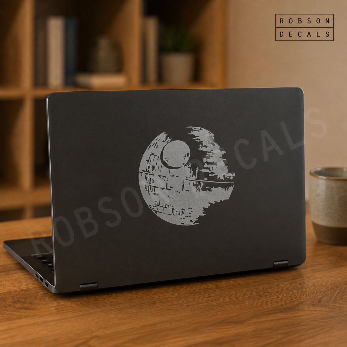 Metallic silver Death Star decal on a dark laptop lid, as pictured. Robson Decals logo and watermark.