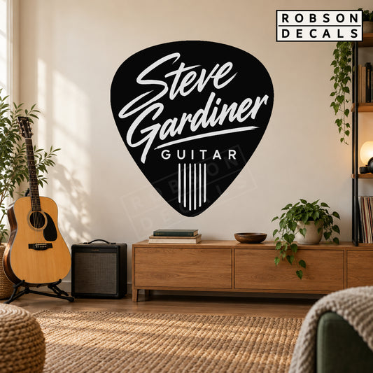 Personalised guitar pick decal in black with white Steve Gardiner lettering on a warm music studio wall