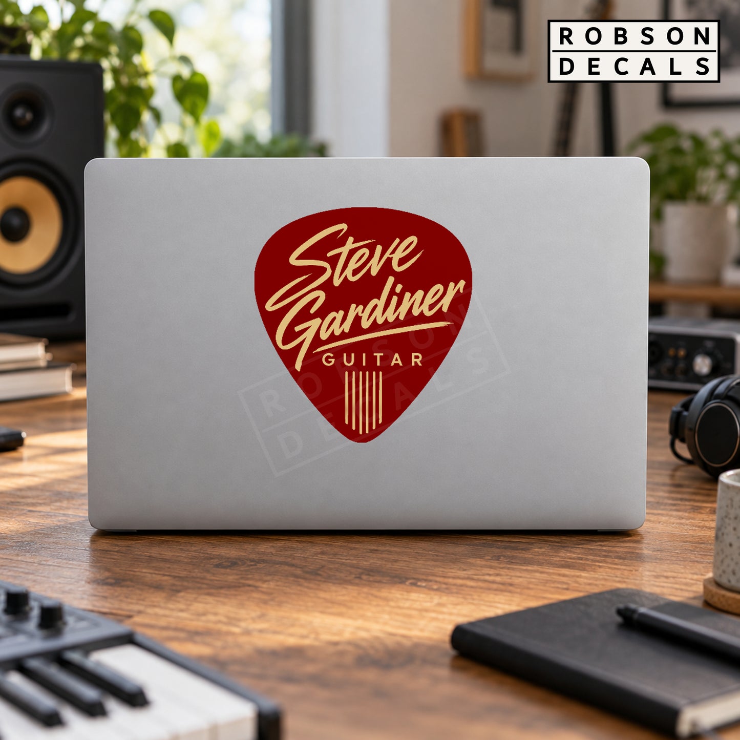 Burgundy guitar pick decal with cream personalised lettering on a silver laptop