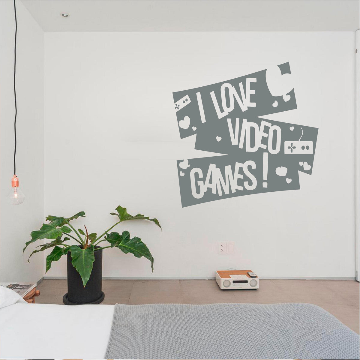 Grey I Love Video Games wall decal with controllers and hearts above a bedside ledge with a plant and radio.