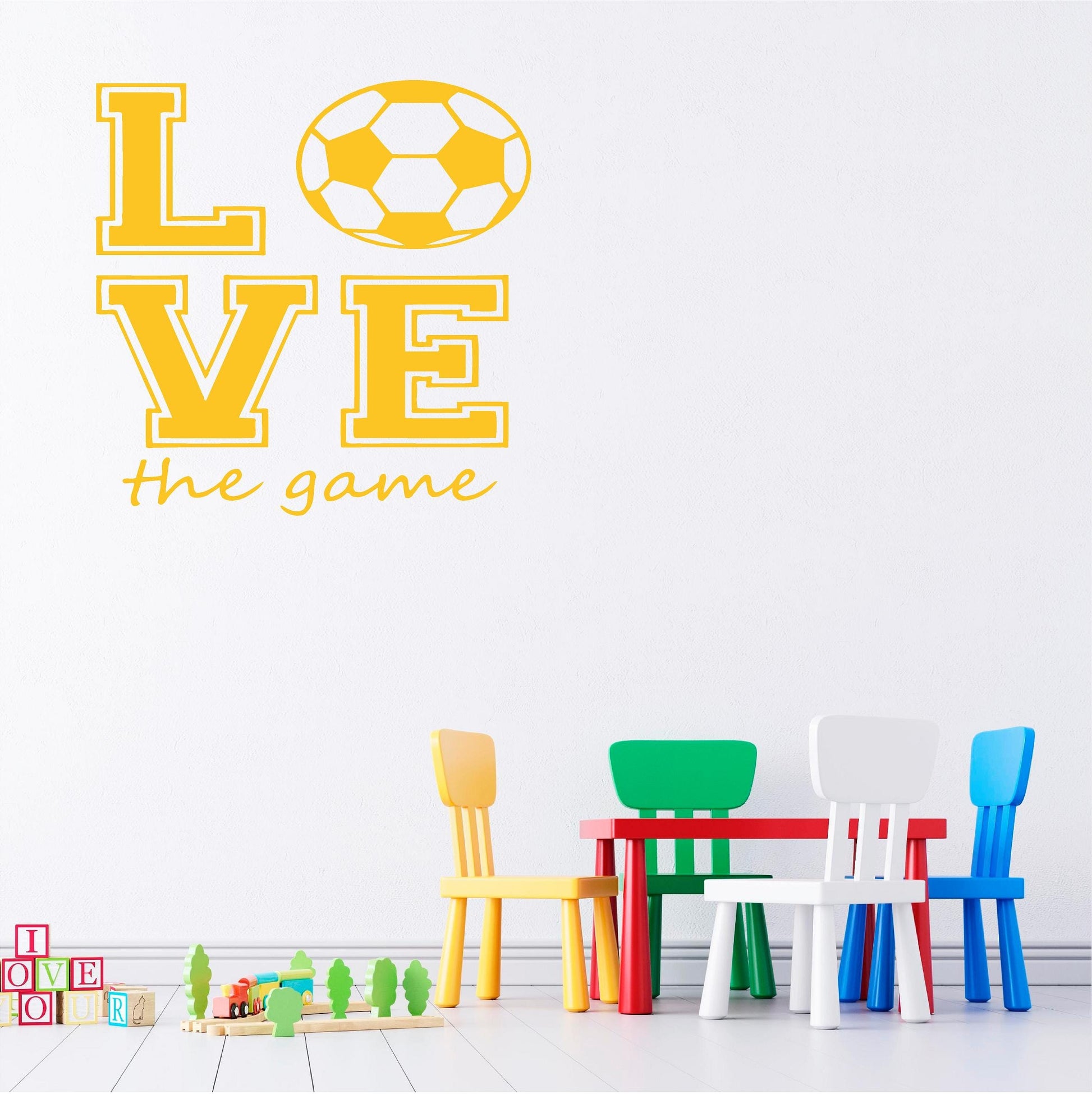 Yellow Love the Game football wall decal above a colourful play table and chairs.