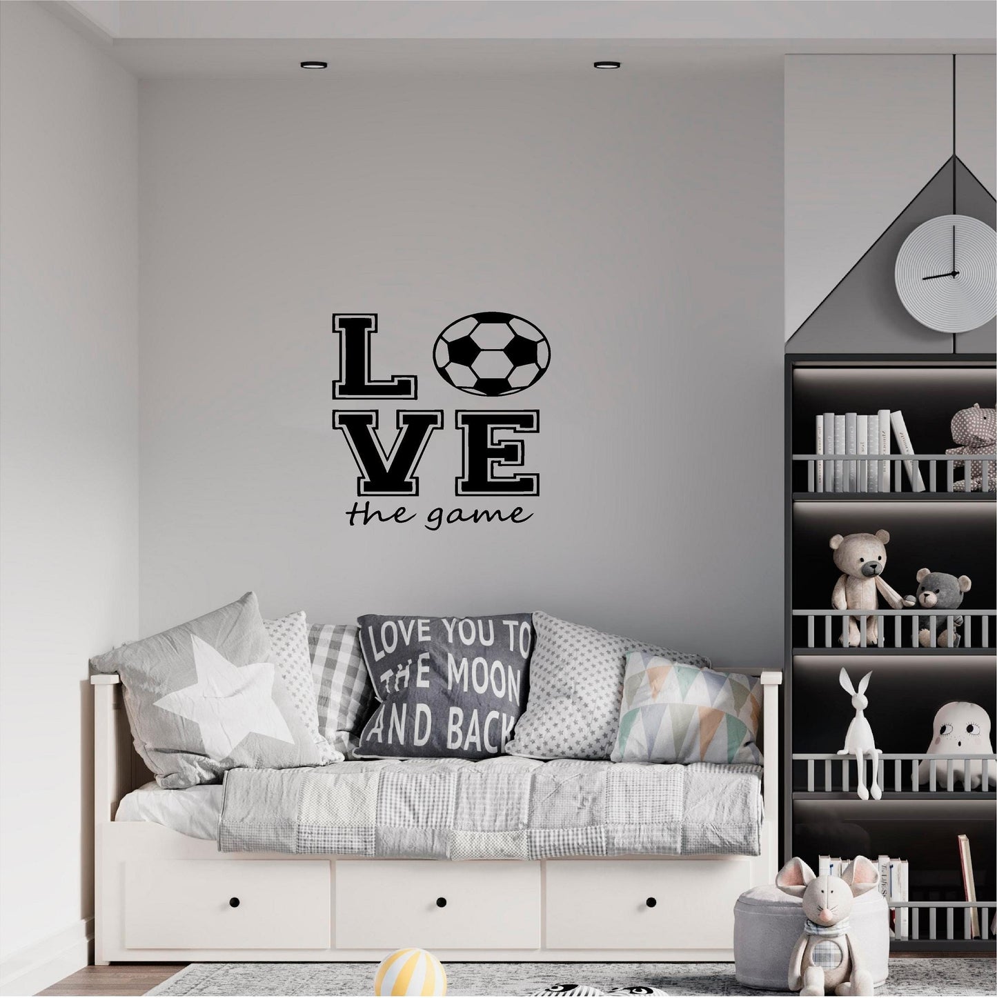 Black Love the Game football wall decal above a grey daybed beside toy shelves.