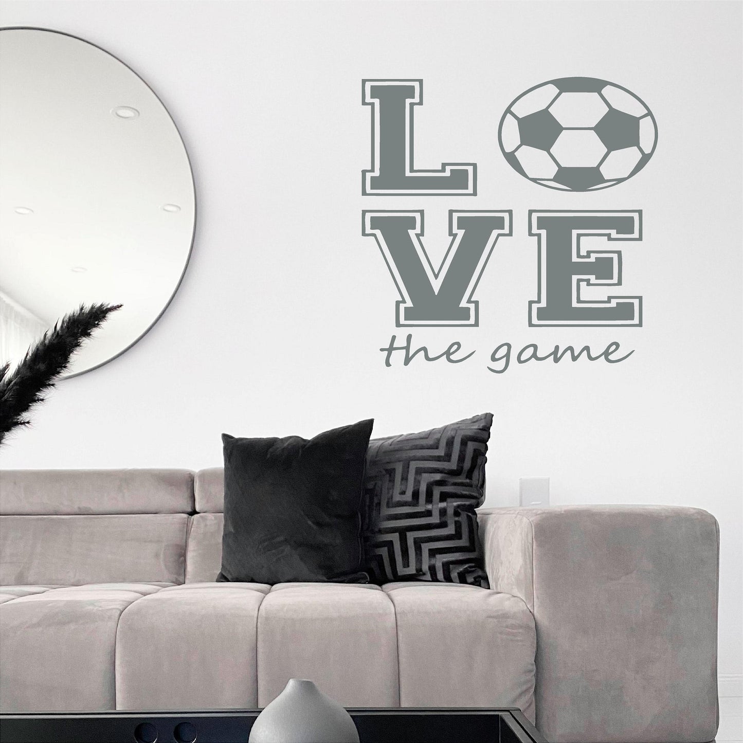 Grey Love the Game football wall decal above a sofa beside a round wall mirror.