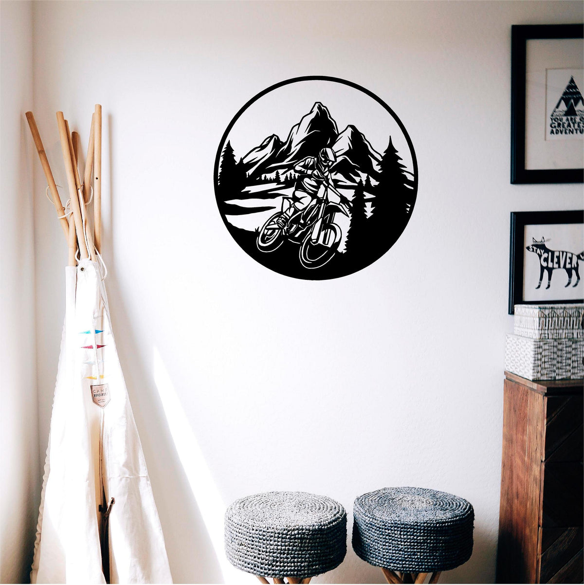 Black circular mountain biker wall decal with mountains and pine trees in a child's room beside a play teepee.