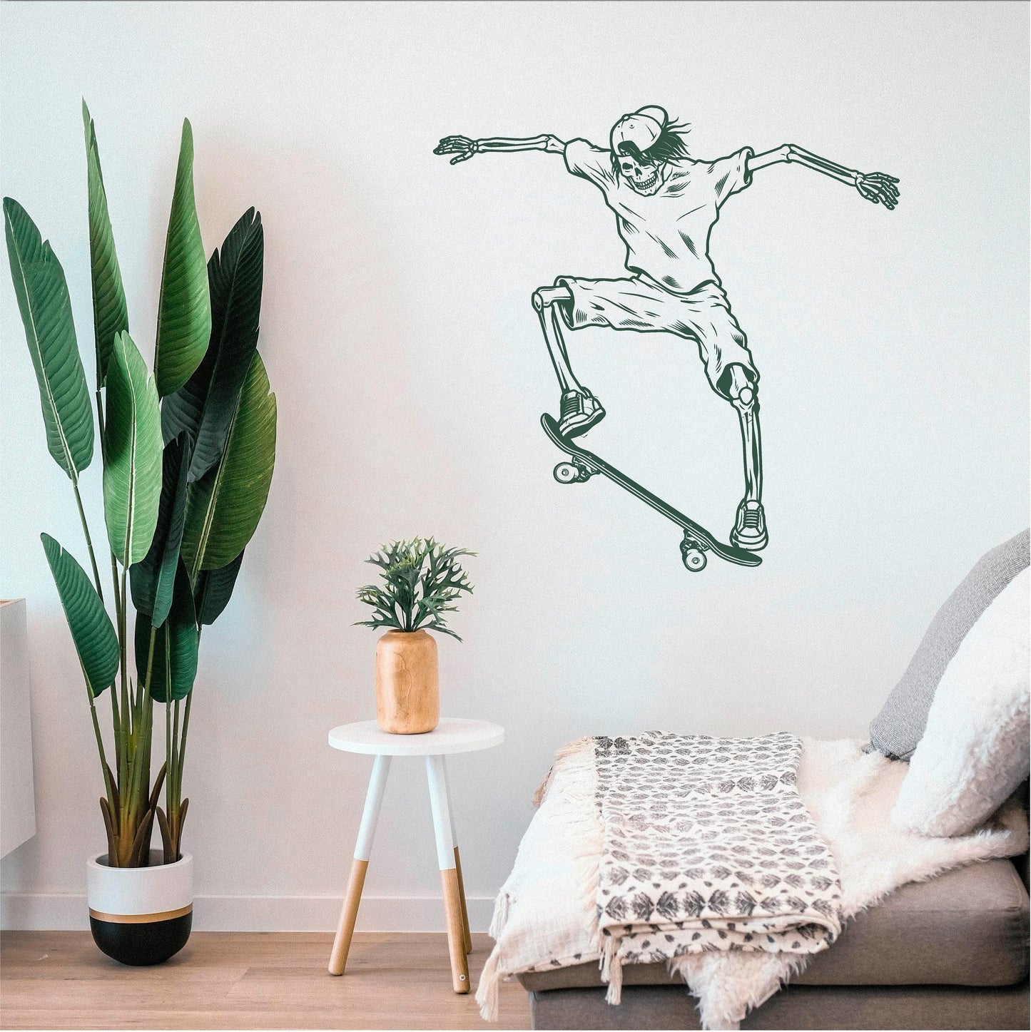 Dark green skeleton skateboarder wall decal above a bench beside a large plant.