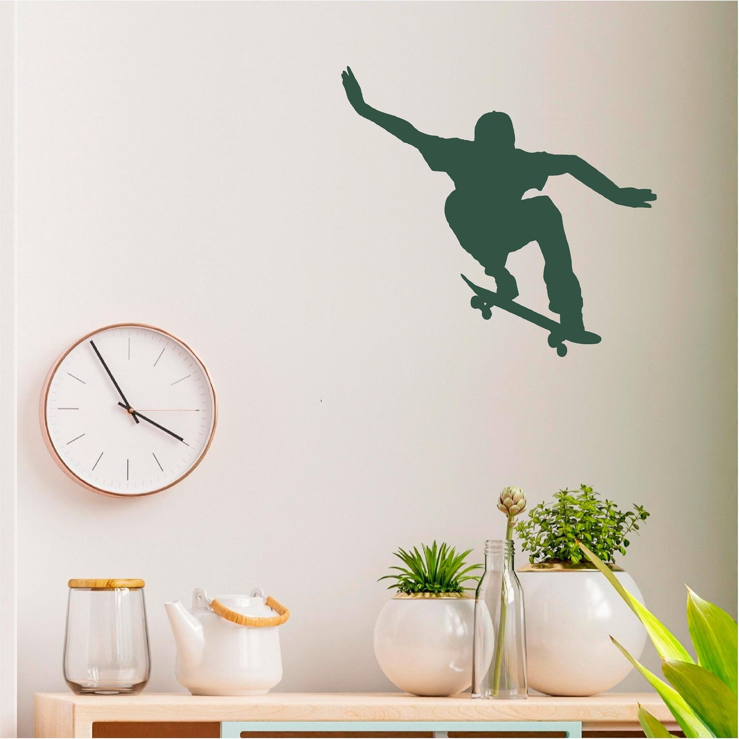 Dark green ollie skateboarder wall decal above a cabinet with plants