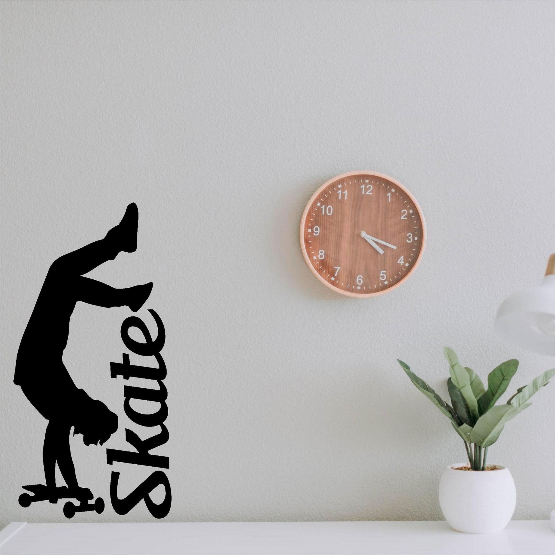 Black handstand skater wall decal beside a clock and plant