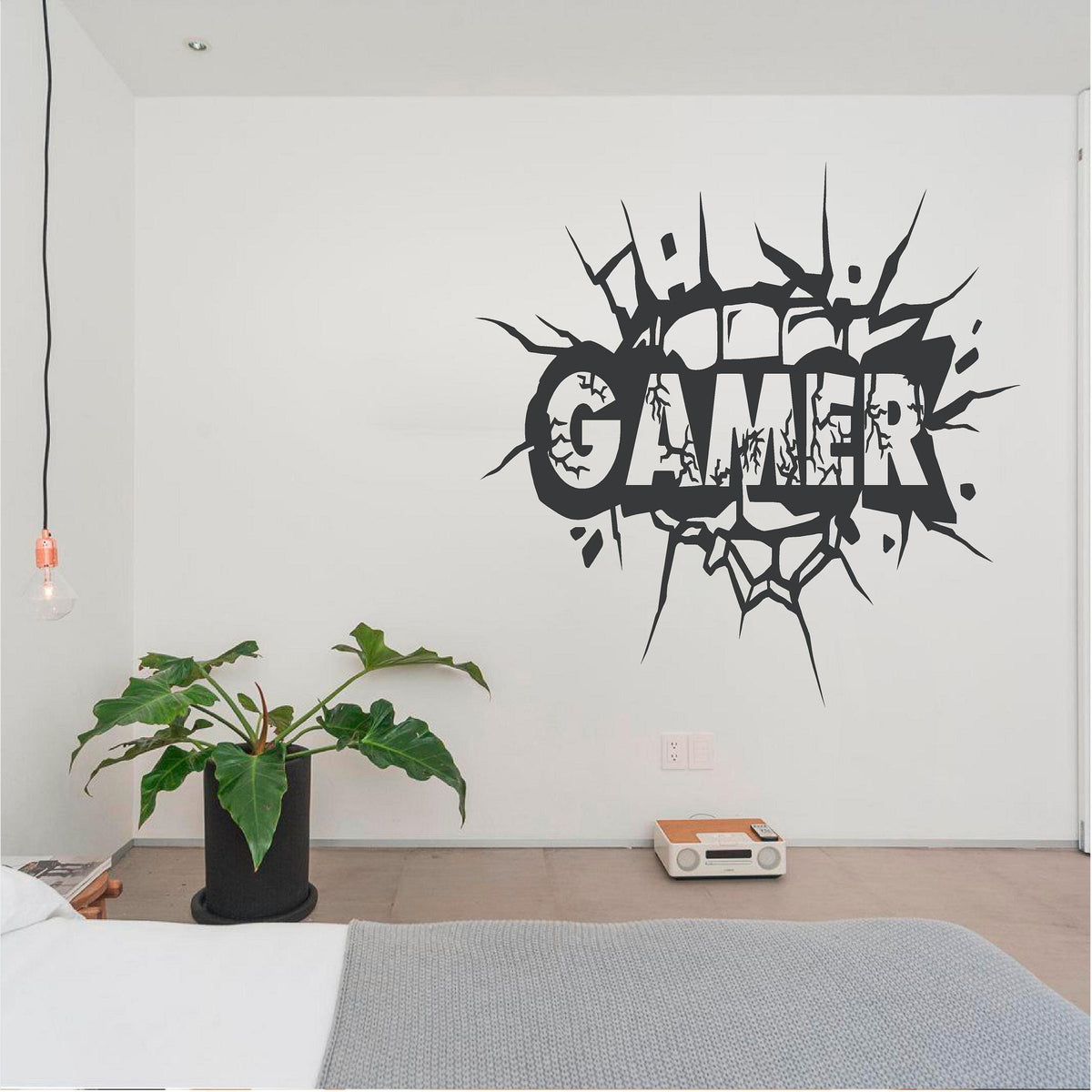Black Gamer cracked-wall decal above a bed beside a plant