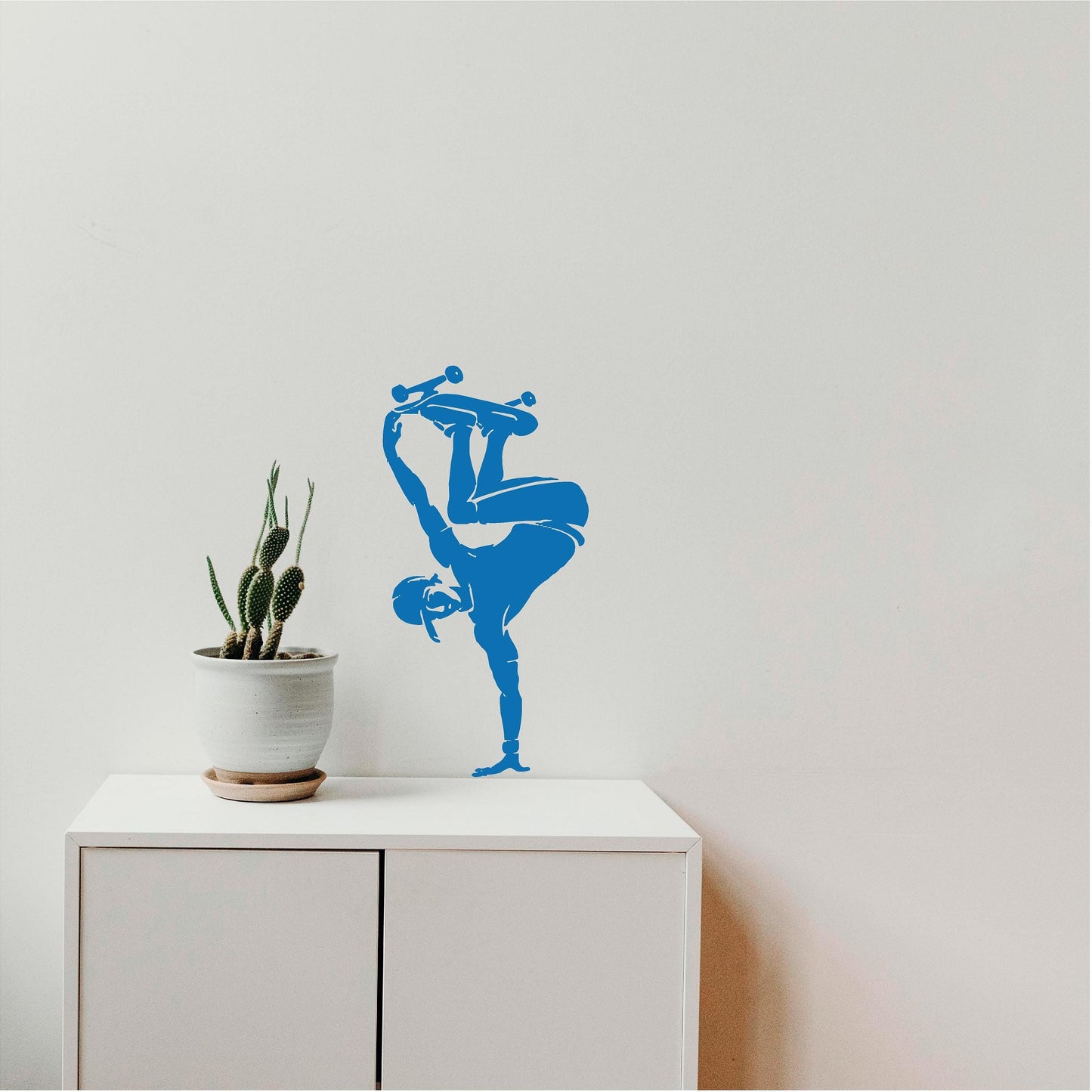 Blue skateboarder handplant wall decal beside a cactus