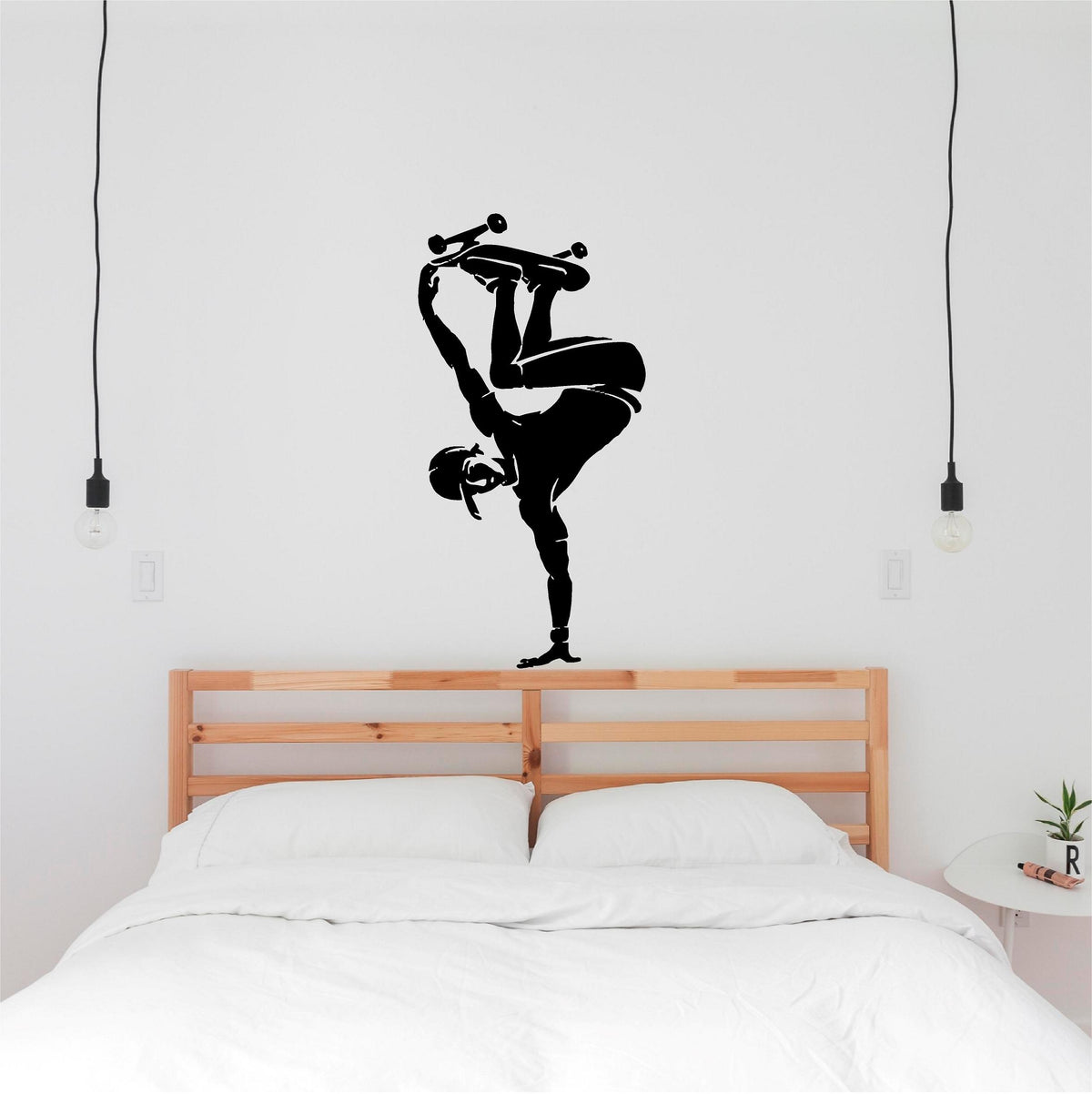 Black skateboarder handplant wall decal above a wooden bed