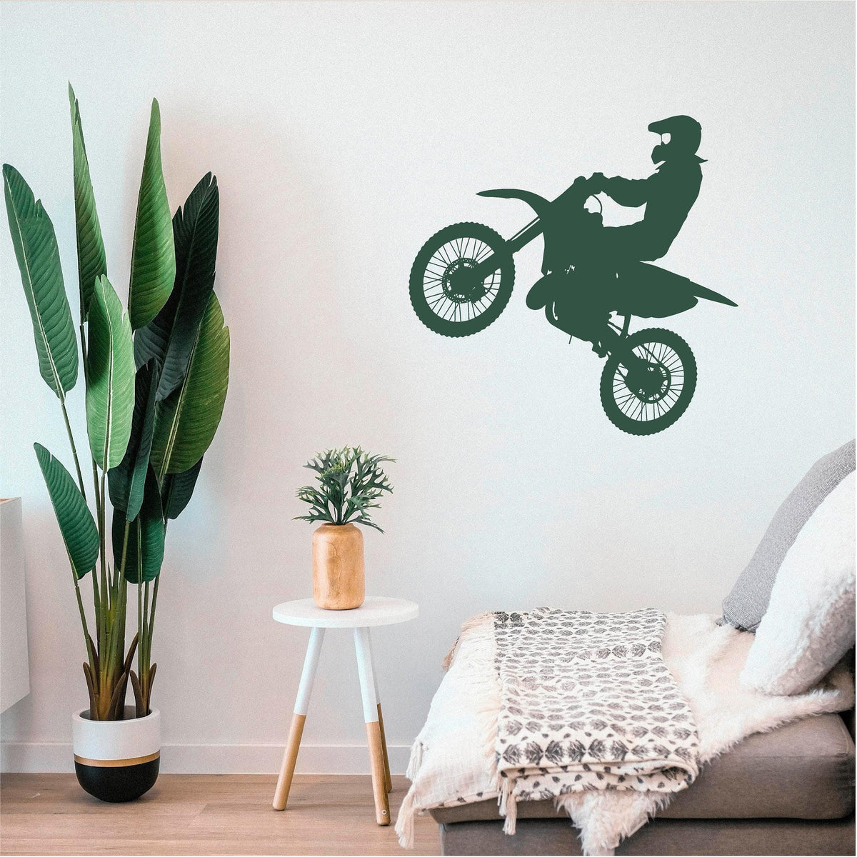 Green motocross rider wall decal beside a bed and tall plant