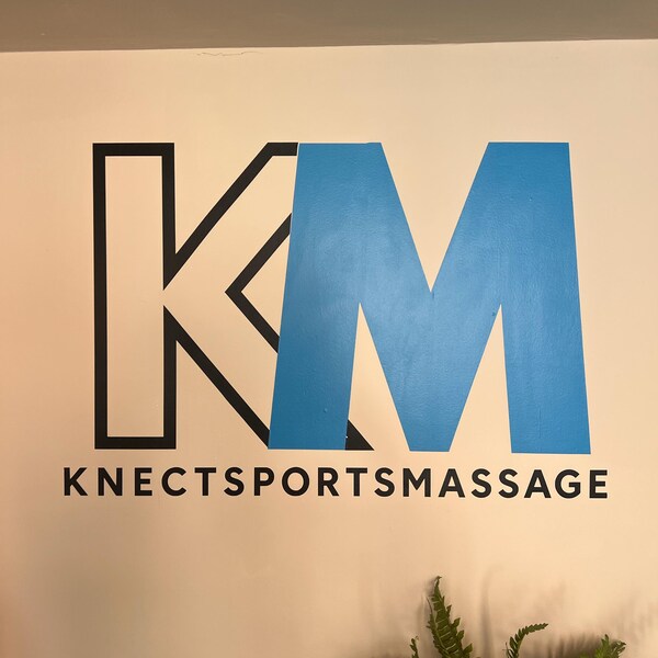 Large blue and black Knect Sports Massage logo on a wall.