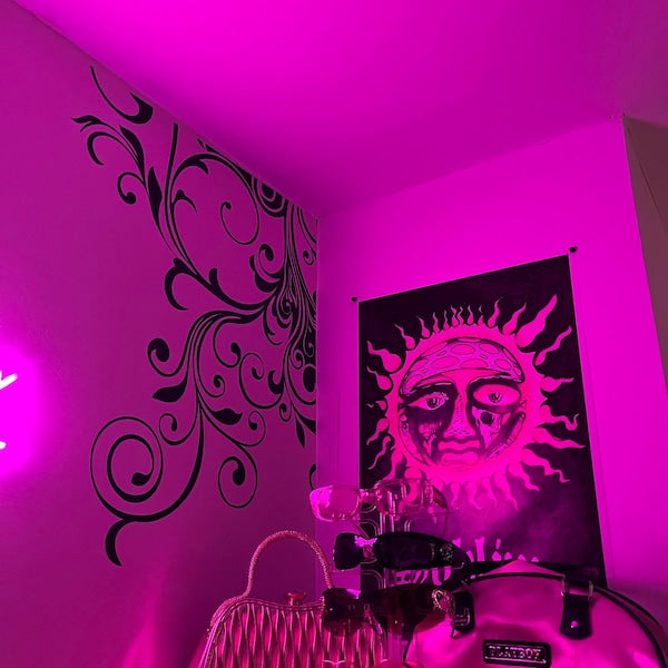 Black floral corner decal on a bedroom wall under pink lighting.