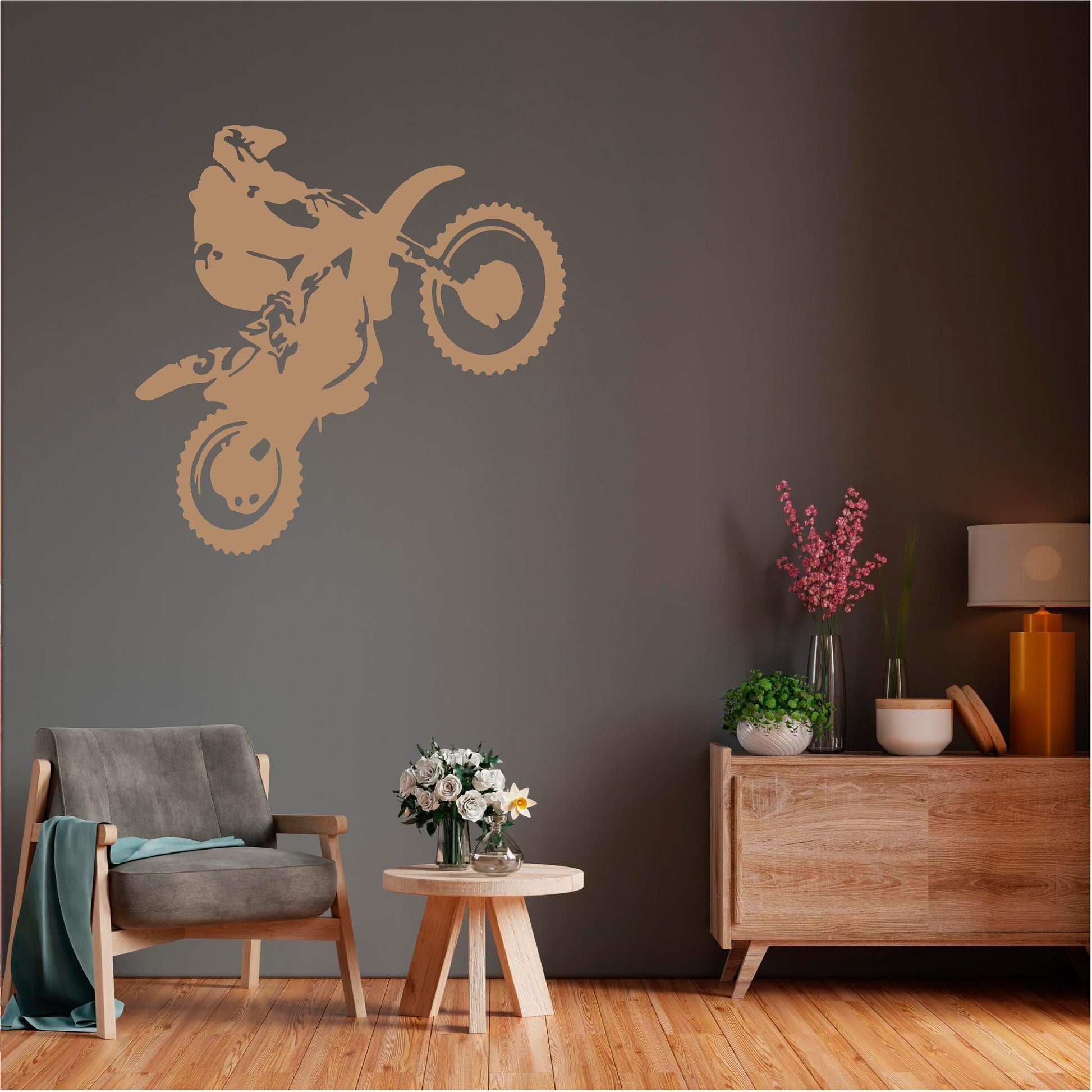 Tan motorbike wheelie rider wall decal on a dark wall above a grey armchair.