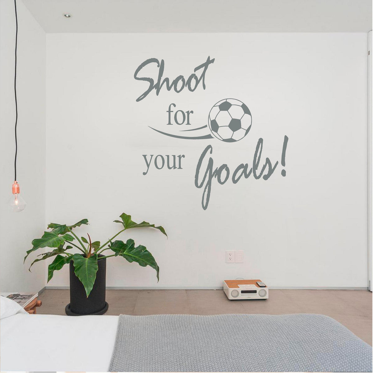 Grey Shoot for your Goals football wall decal beside a houseplant