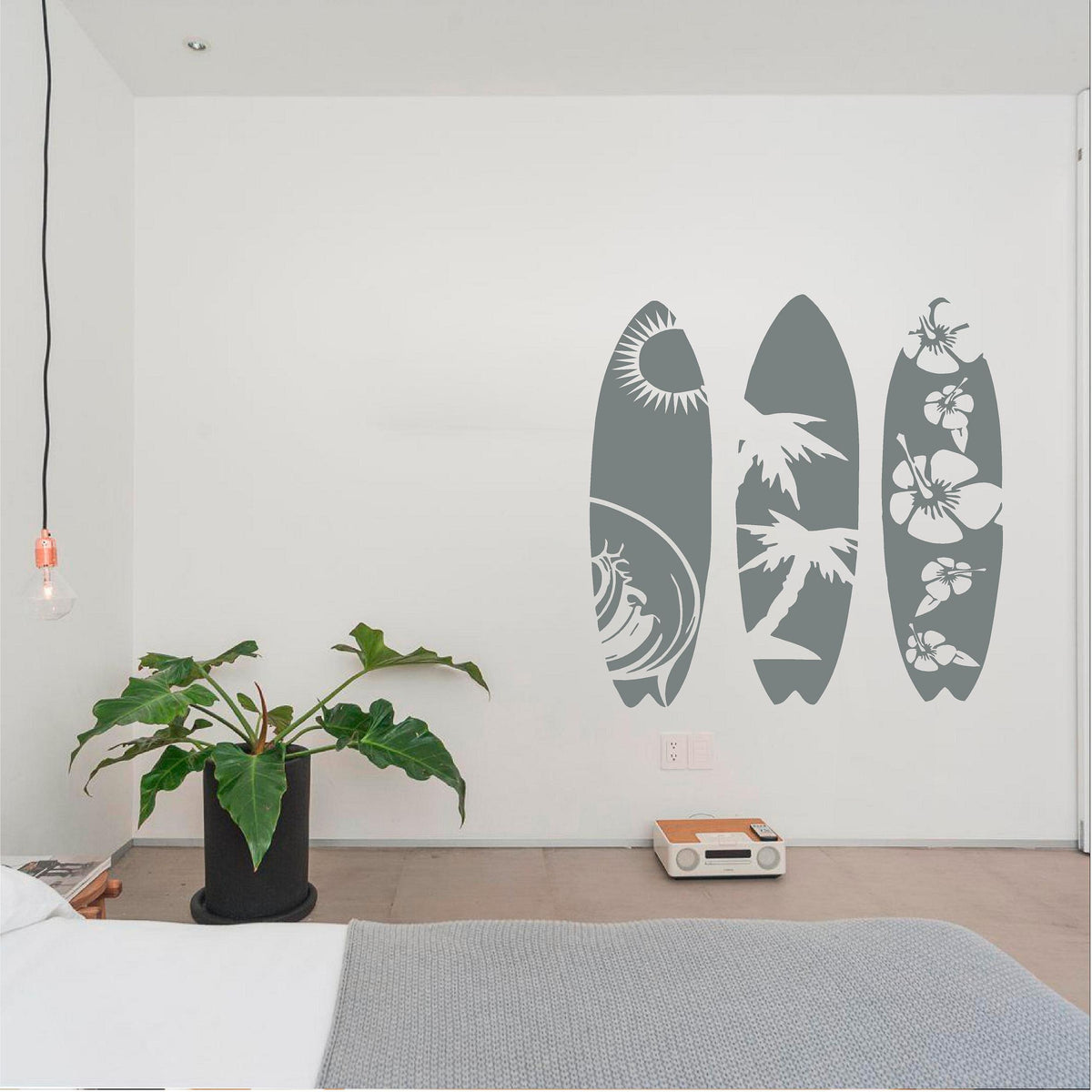 Grey tropical surfboard wall decal set beside a houseplant