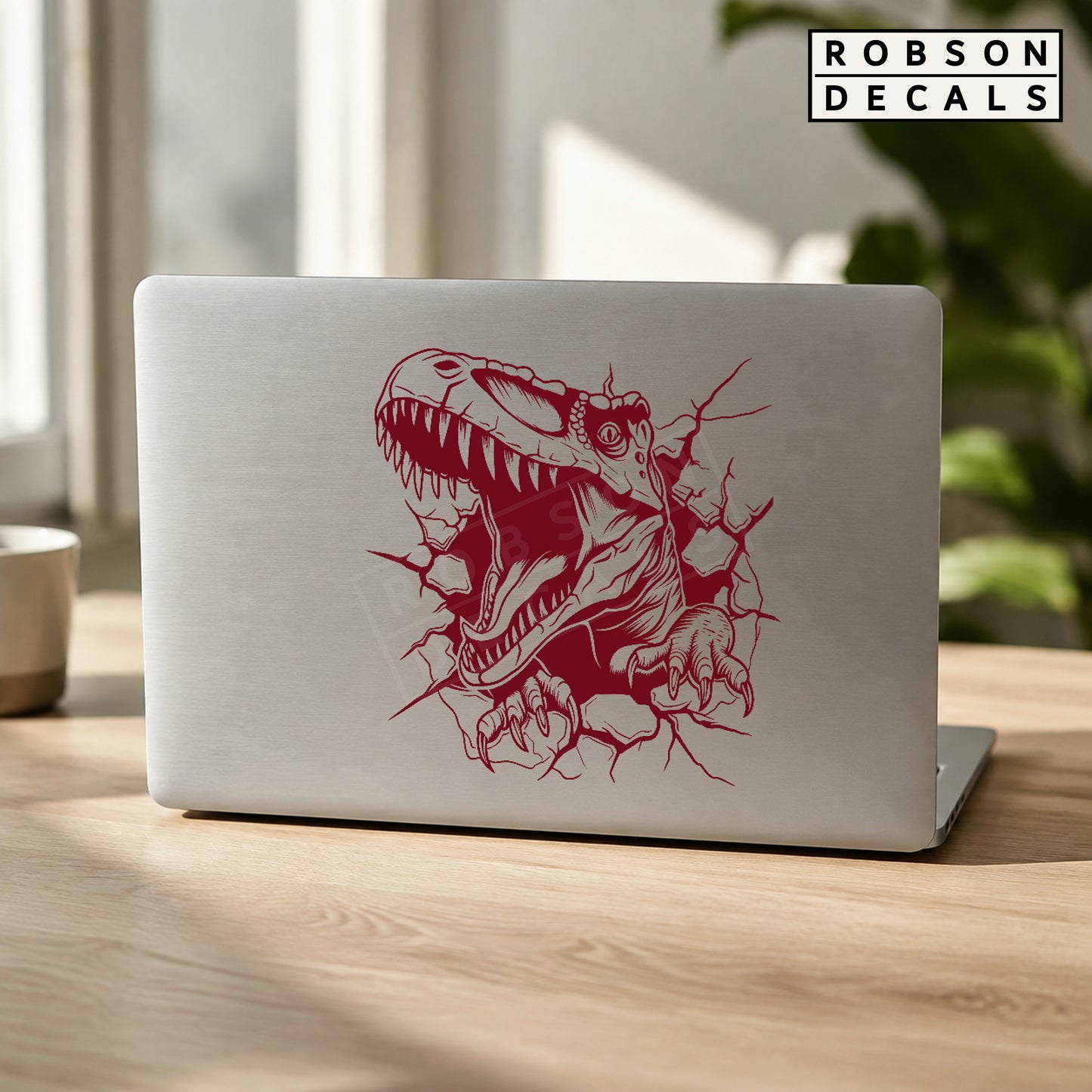 T. rex dinosaur decal in burgundy on a silver laptop.